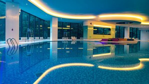 Una piscina interior moderna amb una vista clara de l'entorn, incloent seients i una escala.