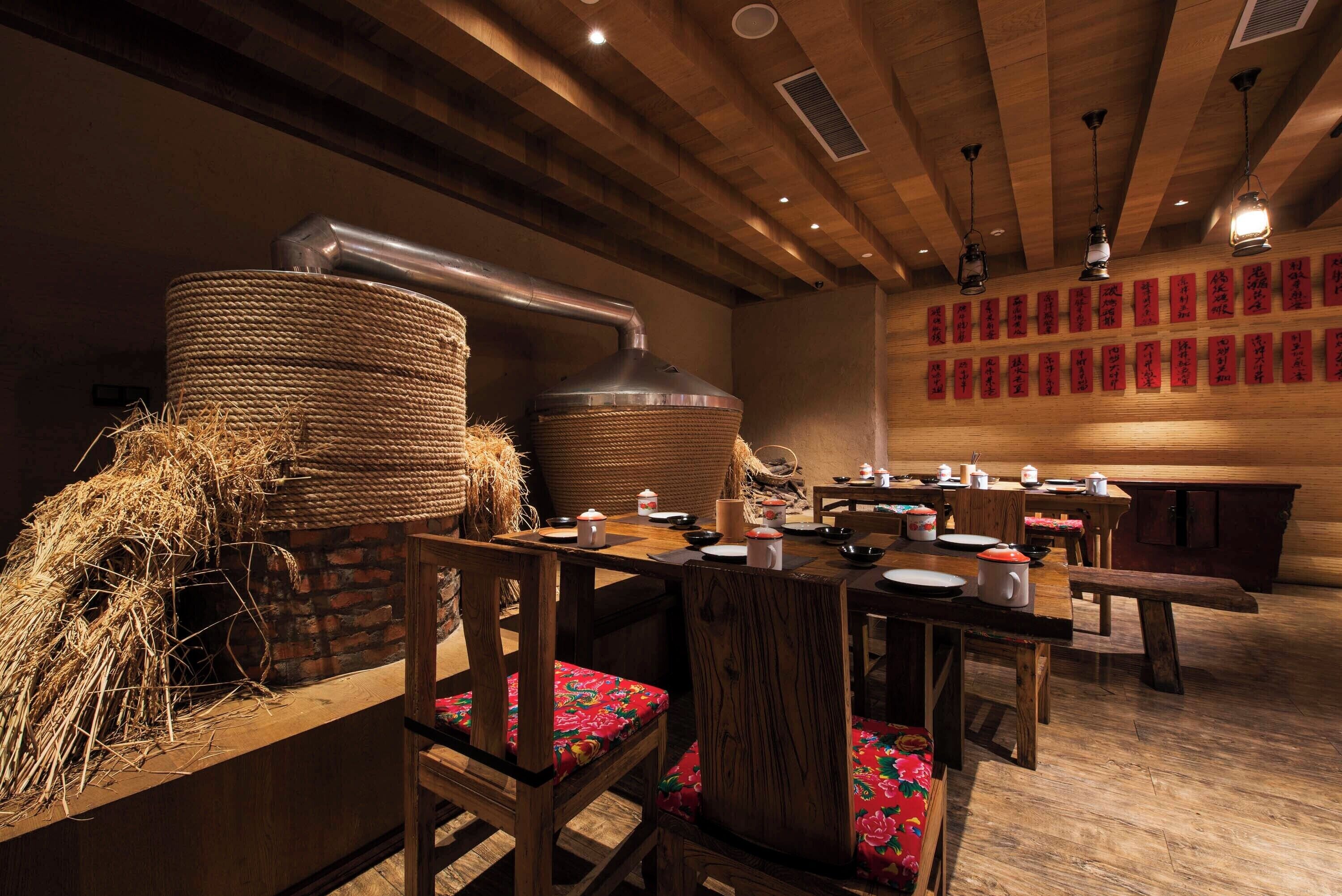 L’intérieur d’un restaurant japonais traditionnel, avec des meubles en bois, une table centrale et un mur orné de calligraphies rouges.