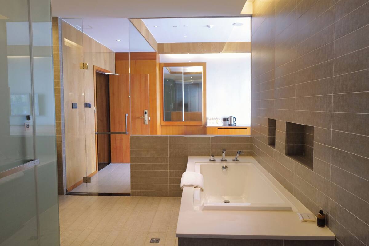 A modern bathroom with a large bathtub, a glass shower enclosure, and a wooden vanity.