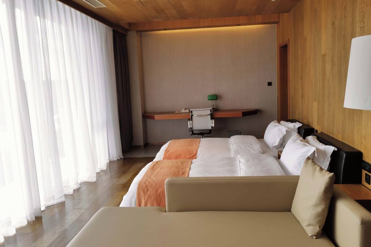 A hotel room with a bed, a desk, and a lamp.