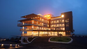 A multi-story hotel with a prominent sign, multiple balconies, and a well-lit entrance. - Le Crown Hotel (Vagamon)