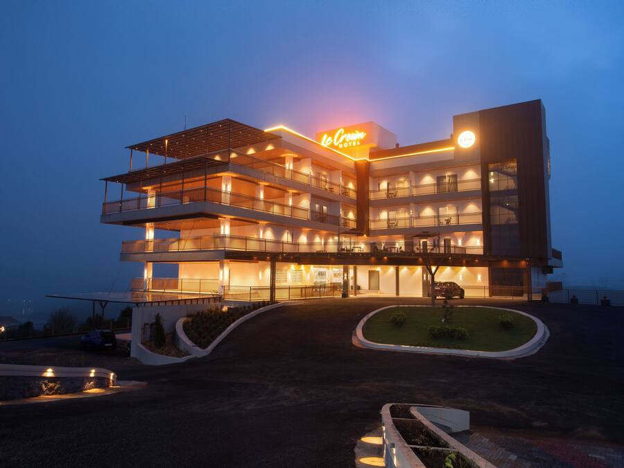 Un hotel de varios pisos con un letrero llamativo, varios balcones y una entrada bien iluminada.
