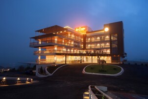 A multi-story hotel with a prominent sign, multiple balconies, and a well-lit entrance.