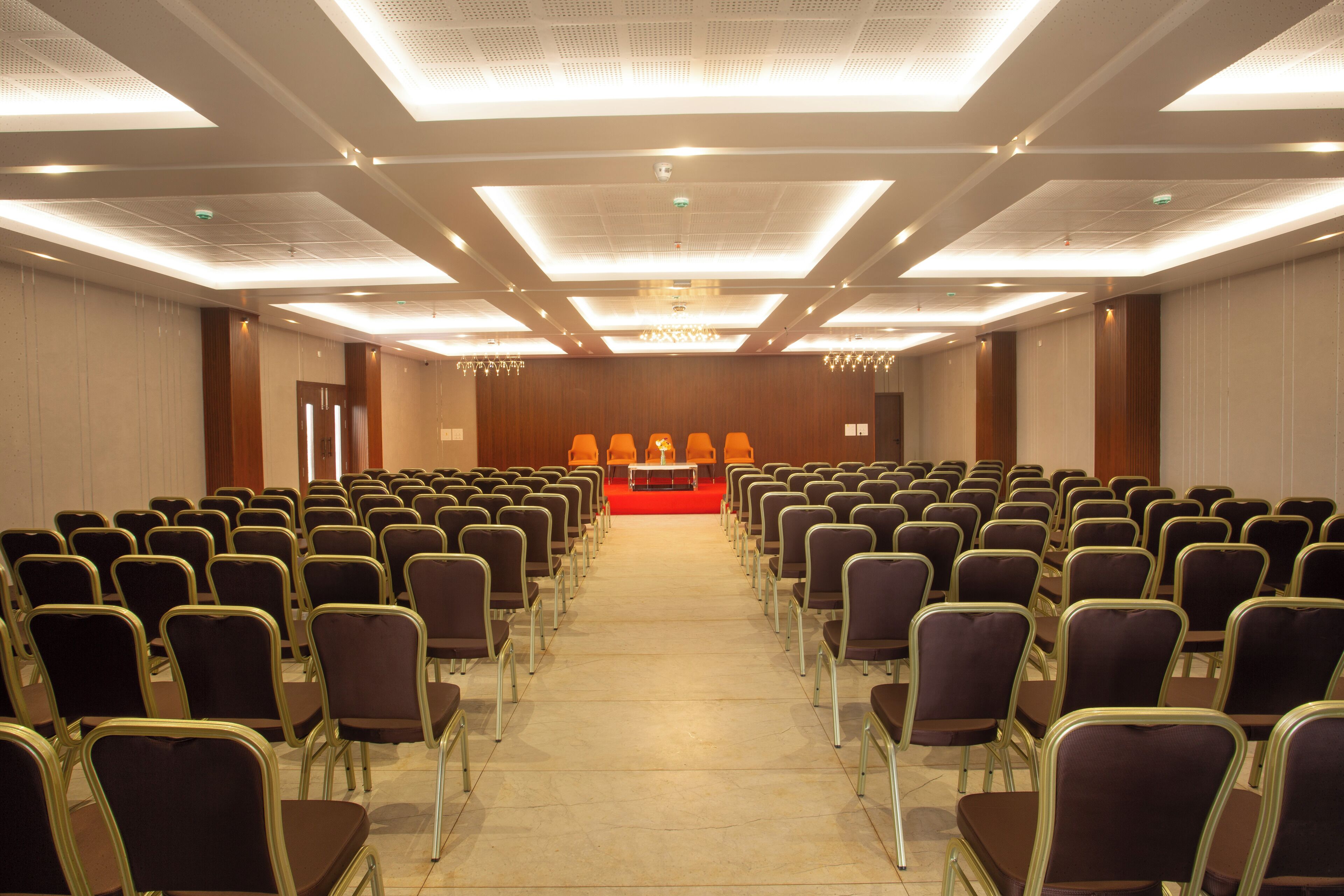 Un salón de conferencias con filas de sillas mirando hacia un escenario con un atril.