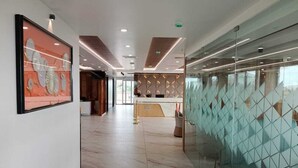A modern hotel lobby with a marble floor, a reception desk, and a glass partition with geometric patterns. - Le Crown Hotel (Vagamon)
