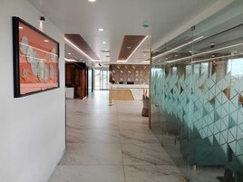A modern hotel lobby with a marble floor, a reception desk, and a glass partition with geometric patterns.