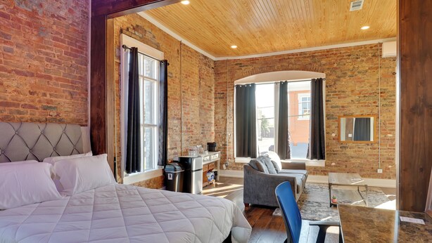 A bedroom with a large bed, a desk, a chair, a sofa, and a view of the outside. - Walk to Courthouse Sq! Loft-Style Marshall Studio (Marshall)