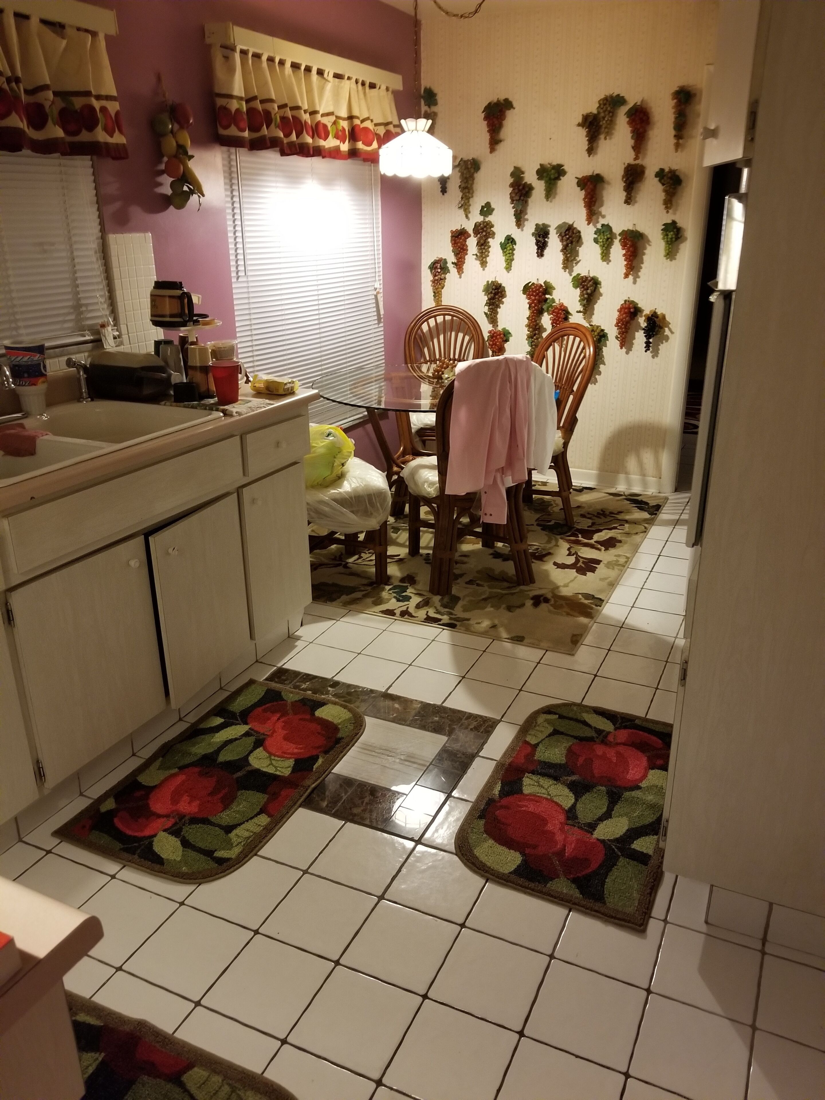 A kitchen with a dining table, chairs, a refrigerator, and a sink.