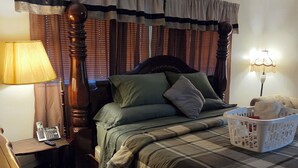 Ein Schlafzimmer mit einem Bett, einem Nachttisch, einer Lampe, einem Telefon und einem Wäschekorb.