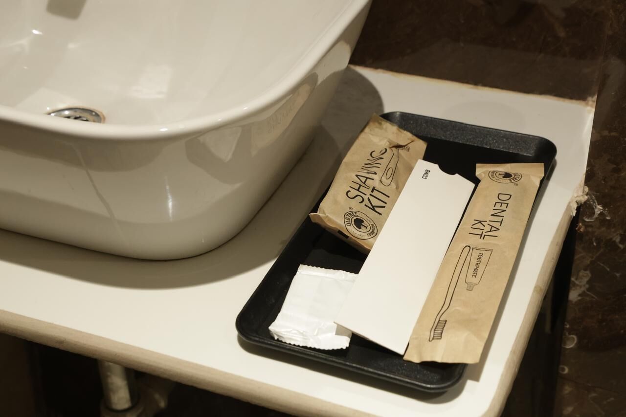 A bathroom sink with a white basin and a black tray holding dental care items.