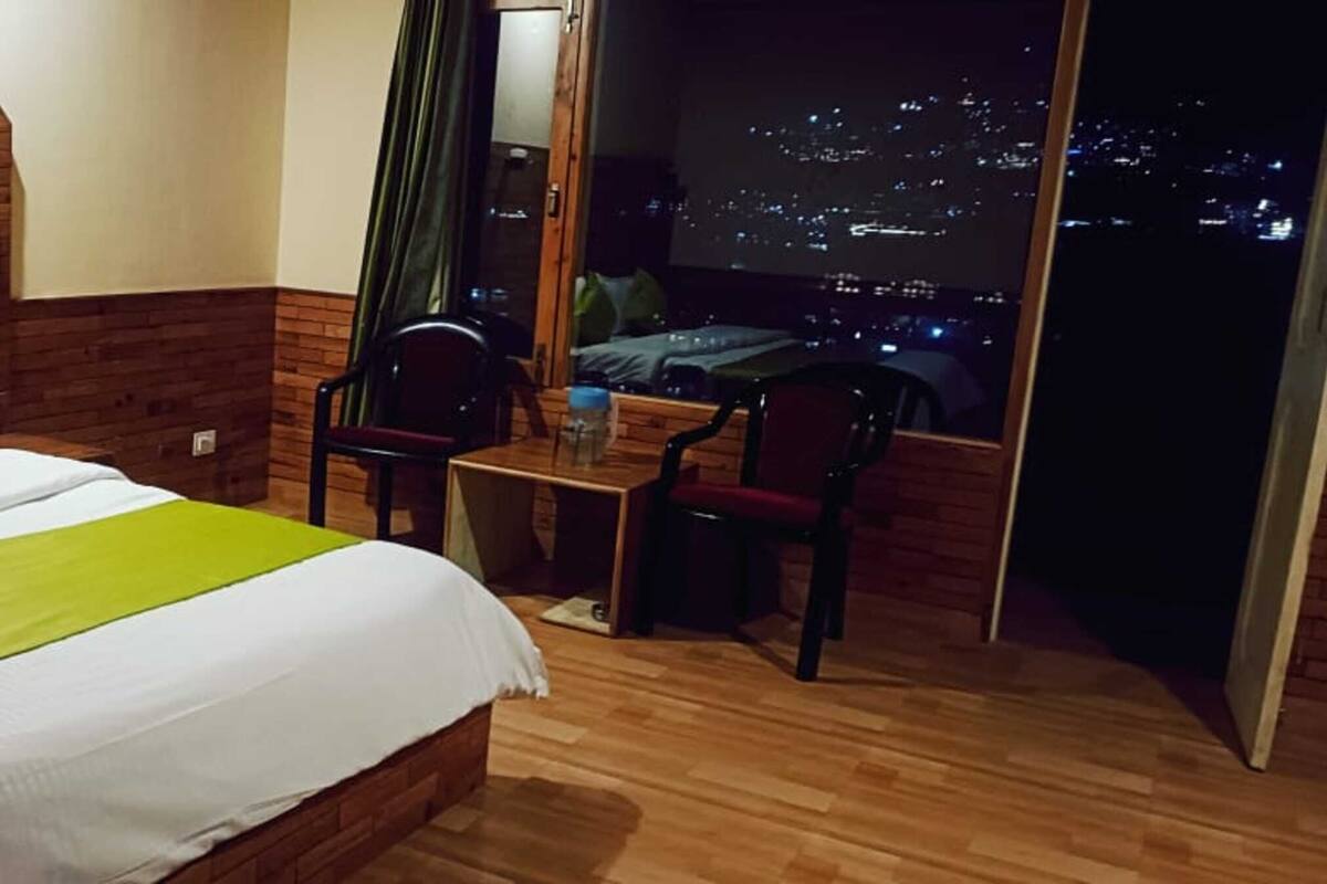Ein Hotelzimmer mit Bett, Tisch und Stuhl. Ein Fenster bietet Blick auf die Stadt.