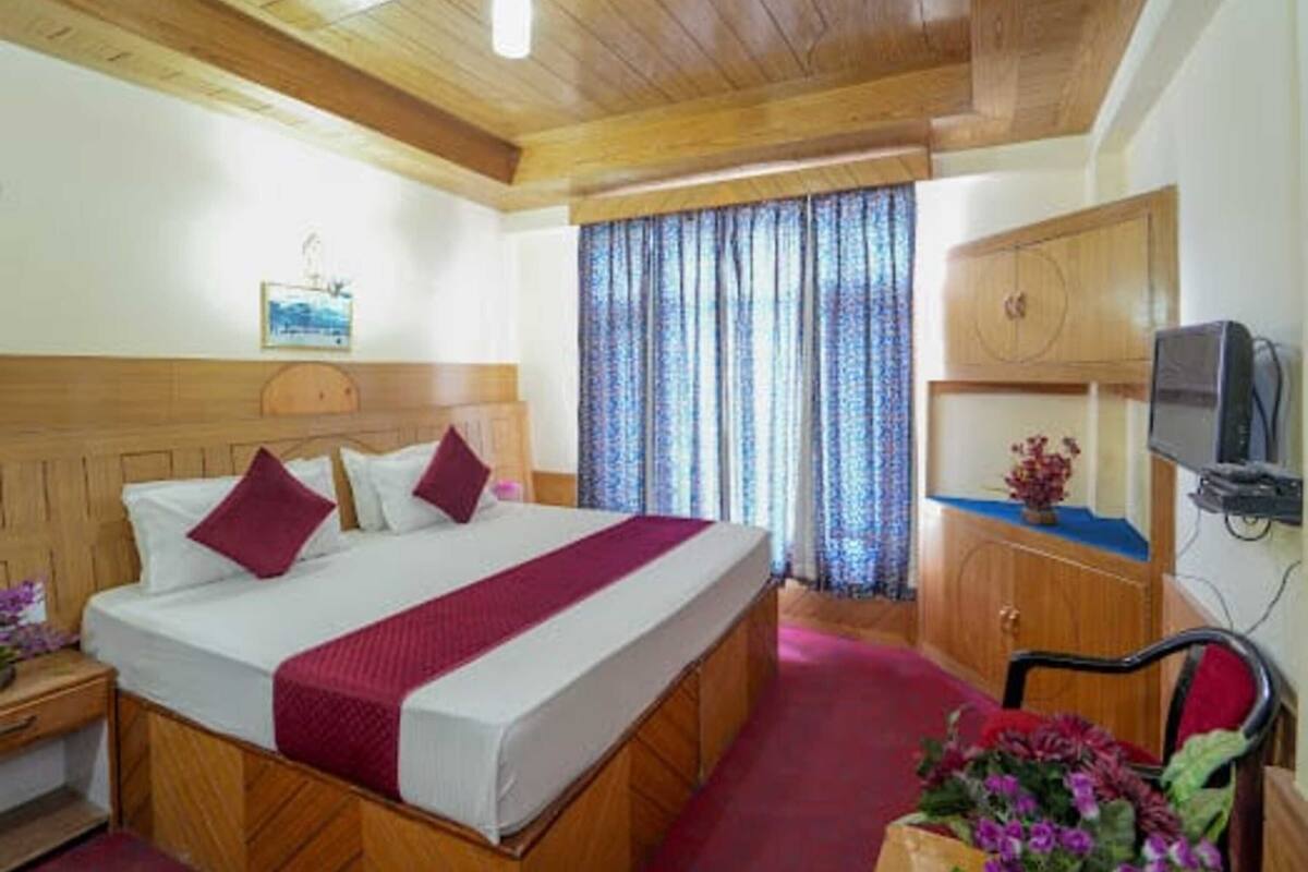 Ein Hotelzimmer mit einem hölzernen Bett, einem Fernseher und einem Schreibtisch.