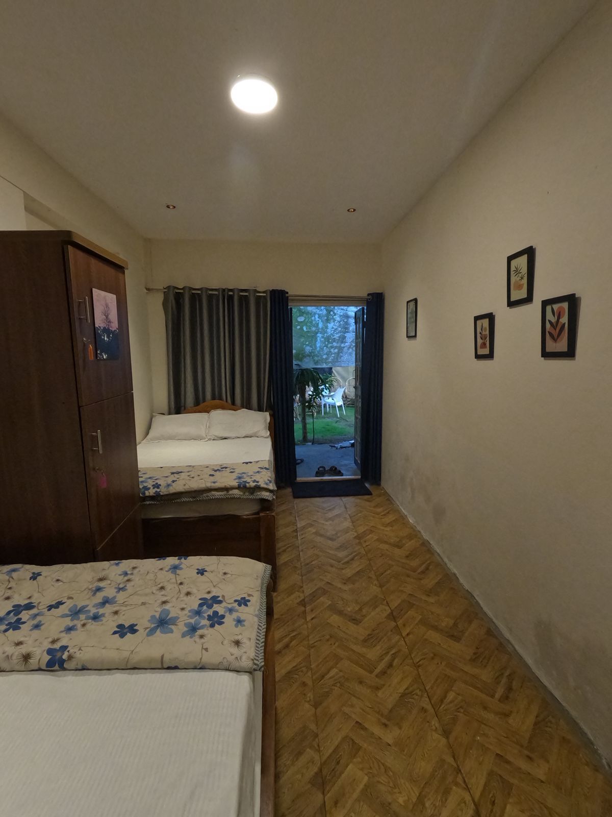 Una habitación con dos camas, un armario y una puerta que da al exterior.