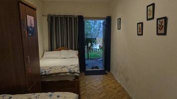 Una habitación con dos camas, un armario y una puerta que da al exterior.