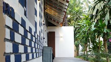 A covered outdoor area with a tiled wall, a concrete floor, and a door leading inside.