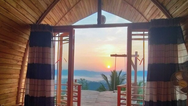 Una habitación con techo de madera y un amplio ventanal abierto que da a una terraza al aire libre.