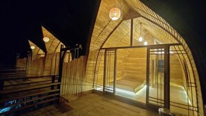 Una serie de estructuras de madera en arco, con iluminación interior, posiblemente un hotel o resort.