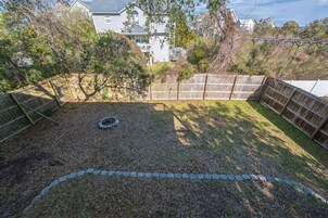 Un patio trasero con cerco de madera, un cantero circular y una zona con césped.