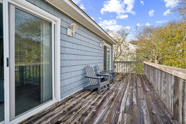 A wooden deck with two Adirondack chairs and a glass door leading to a porch. - Walk to Beach Private Deck Family Fun (Holly Ridge)