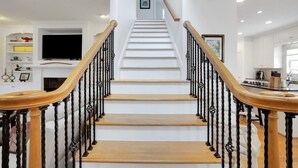 A staircase with wooden steps and black balusters, leading to a landing with a framed picture. - Augusta Getaway Near Masters Porch Swing Deck (Augusta)