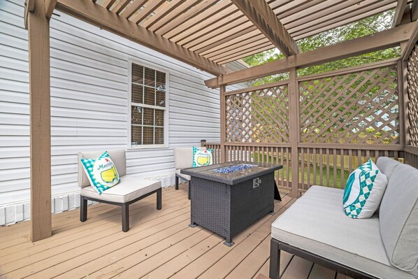 A covered outdoor seating area with a table and two chairs, a wooden pergola, and a lattice fence. - Augusta Getaway Near Masters Porch Swing Deck (Augusta)