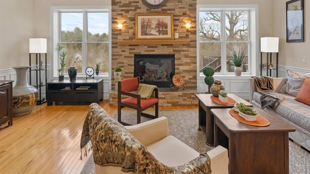 A spacious living room with a stone fireplace, large windows, and a cozy seating area. - Luxury Ann Arbor Stay Theater Gym Game Room Spa (Ann Arbor)