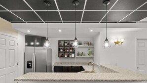 A modern kitchen with a central island, bar stools, pendant lights, and a built-in refrigerator. - Luxury Ann Arbor Stay Theater Gym Game Room Spa (Ann Arbor)