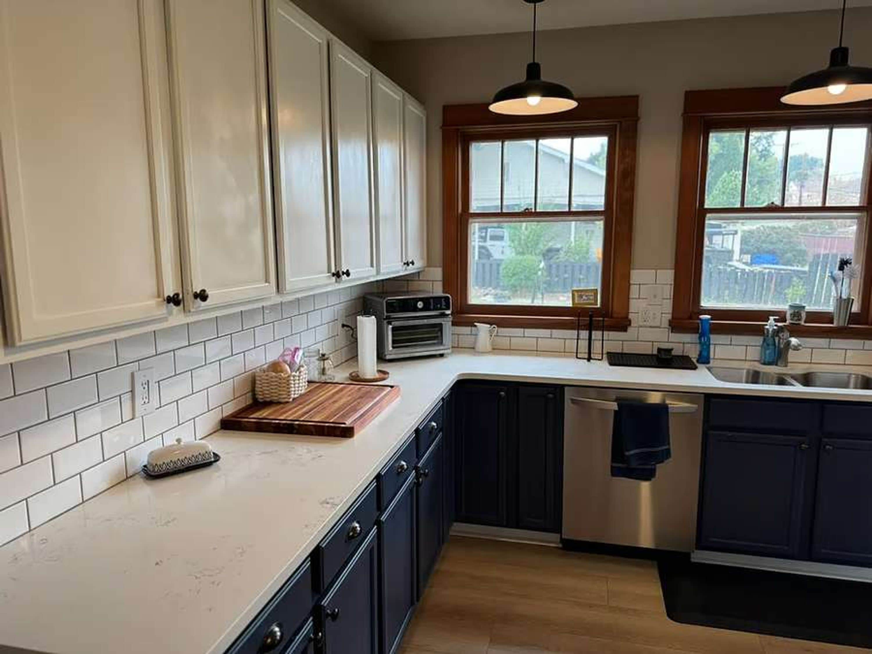 A kitchen with white cabinets, a wooden countertop, a built-in oven, and a window with a view of the outside.
