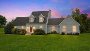 A two-story house with a front porch, a chimney, and a well-maintained lawn. - Waterfront Kent Island Retreat 5BR Sleeps 12 Near Weddings Annapolis (Stevensville)