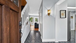 A hallway with a wooden door, a wall-mounted light fixture, and a framed picture. - Waterfront Kent Island Retreat 5BR Sleeps 12 Near Weddings Annapolis (Stevensville)