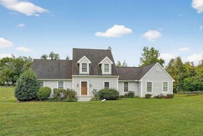 A two-story house with a front porch, a small garden, and a well-maintained lawn. - Waterfront Kent Island Retreat 5BR Sleeps 12 Near Weddings Annapolis (Stevensville)