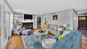 A spacious living room with a fireplace, a television, and a dining area. - Waterfront Kent Island Retreat 5BR Sleeps 12 Near Weddings Annapolis (Stevensville)