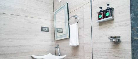 Un baño moderno con inodoro blanco, tocador de madera con lavamanos y un espejo.
