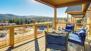 Eine Holzterrasse mit Sitzgelegenheiten und Blick auf eine gebirgige Landschaft.