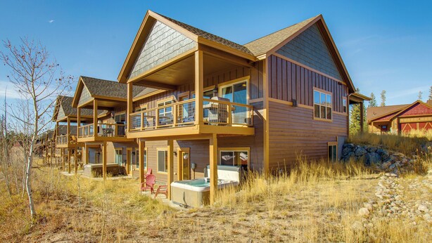 Ein mehrstöckiges Holzhaus mit Balkon, Whirlpool und überdachter Außenlounge.