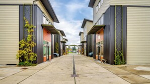 A row of townhouses with a central walkway, each with a garage door and a small bench. - 3 Blocks to Dtwn! Cozy Sedro-Woolley Retreat! (Sedro-Woolley)
