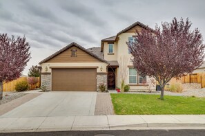 Une maison à deux étages avec une porte de garage marron, une façade en pierre et une pelouse bien entretenue.