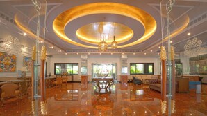 A spacious lobby with a polished marble floor, a central chandelier, and a large circular ceiling design.