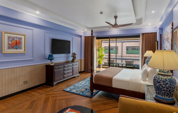A hotel room with a large bed, a television, a dresser, and a view of the outside.