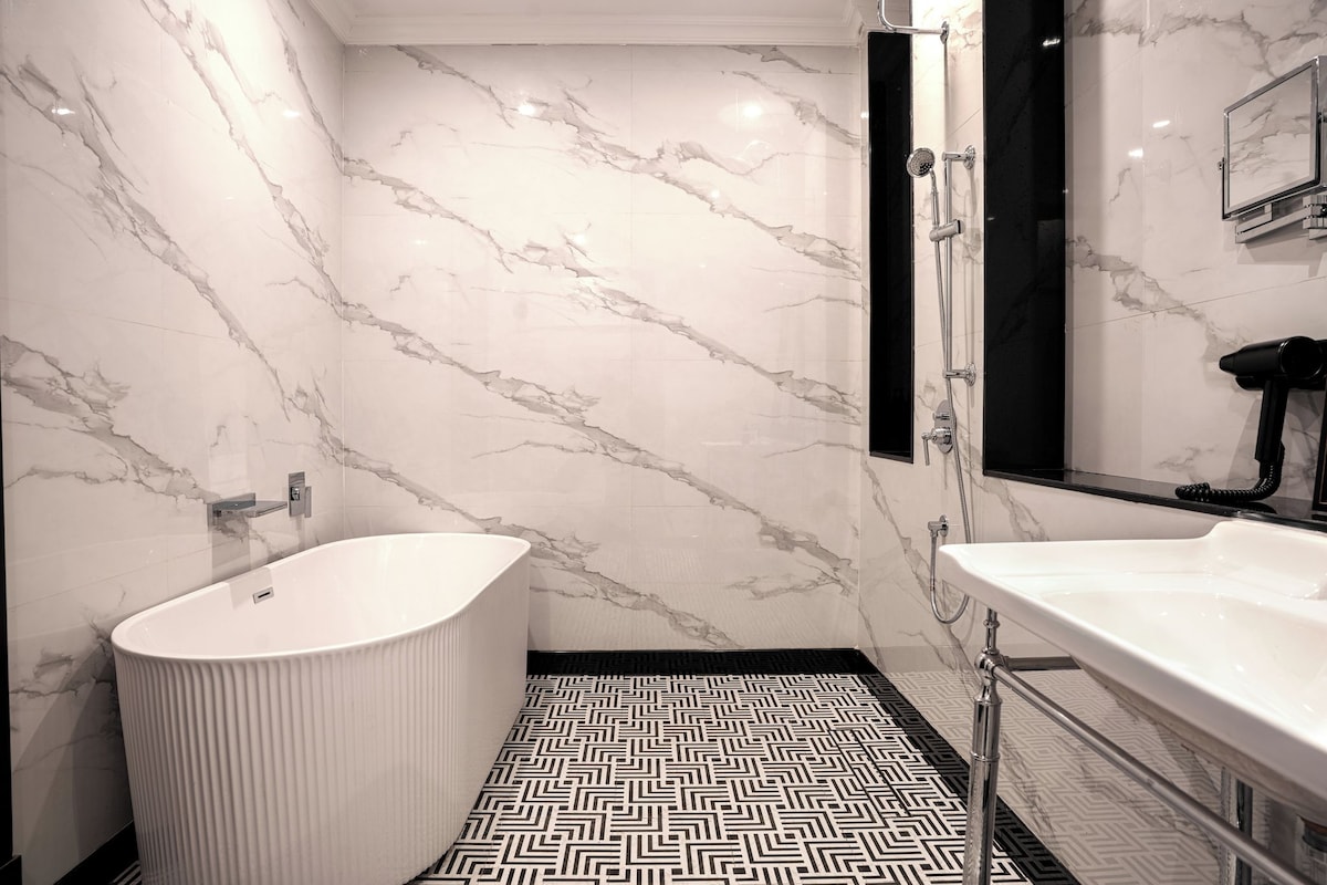 A modern bathroom with a freestanding bathtub, a vanity with a mirror, and a shower area.