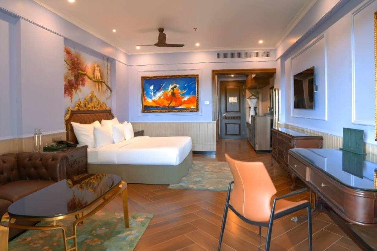 Ett hotellrum med en säng, ett skrivbord, en stol, en tv och en tavla på väggen.