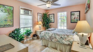 A bedroom with a bed, ceiling fan, potted plants, and artwork on the walls. - Gateway to the Everglades! Tropical Jungle Cottage (Miami)