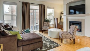 A living room with a fireplace, a ceiling fan, and a large TV. - 1 Mi to Dtwn Cincinnati: Spacious Townhome w/ Deck (Cincinnati)