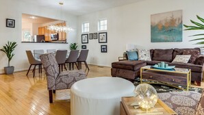 A modern living room with a dining area, a kitchen visible through an open door, and a large painting on the wall. - 1 Mi to Dtwn Cincinnati: Spacious Townhome w/ Deck (Cincinnati)
