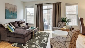 A modern living room with a brown sectional sofa, a patterned armchair, a coffee table, and a large window with curtains. - 1 Mi to Dtwn Cincinnati: Spacious Townhome w/ Deck (Cincinnati)