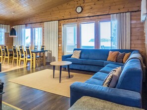 En hyggelig stue med en blå sofa, et rundt sofabord og et spiseområde med træstole og et bord.