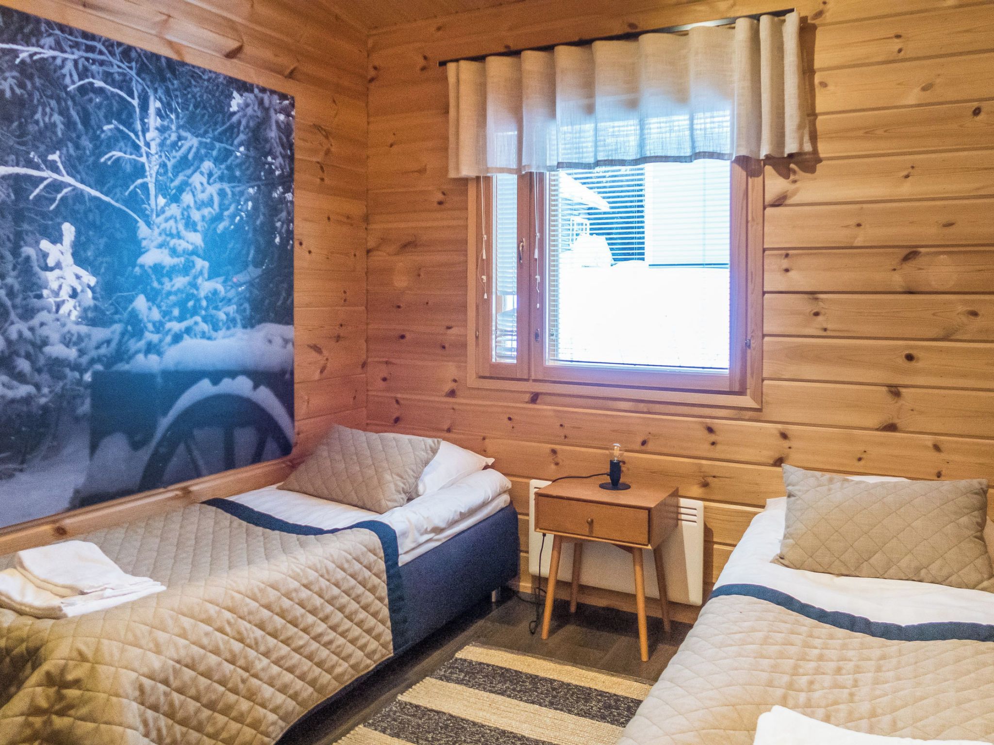 A cabin room with two beds, a small table, and a window with curtains.