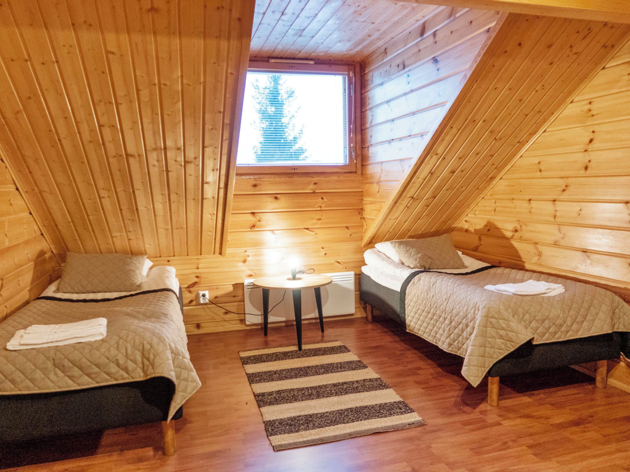 A cabin with two beds, a small table, and a window.