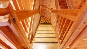 Eine Holztreppe mit Geländer, umgeben von Holzwänden und einem Holzboden.