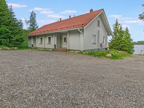 Ein zweistöckiges Haus mit rotem Ziegeldach, einer Veranda und einem Kiesweg.